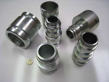 Precision-machined components held to tight tolerances, with a coin for scale
